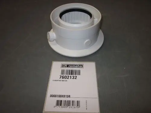 Weißer Kunststoffadapter von Remeha mit einer runden Öffnung und seitlichem Anschluss, auf einem grauen Untergrund platziert. Barcodes und Artikelnummer auf dem Etikett sichtbar.